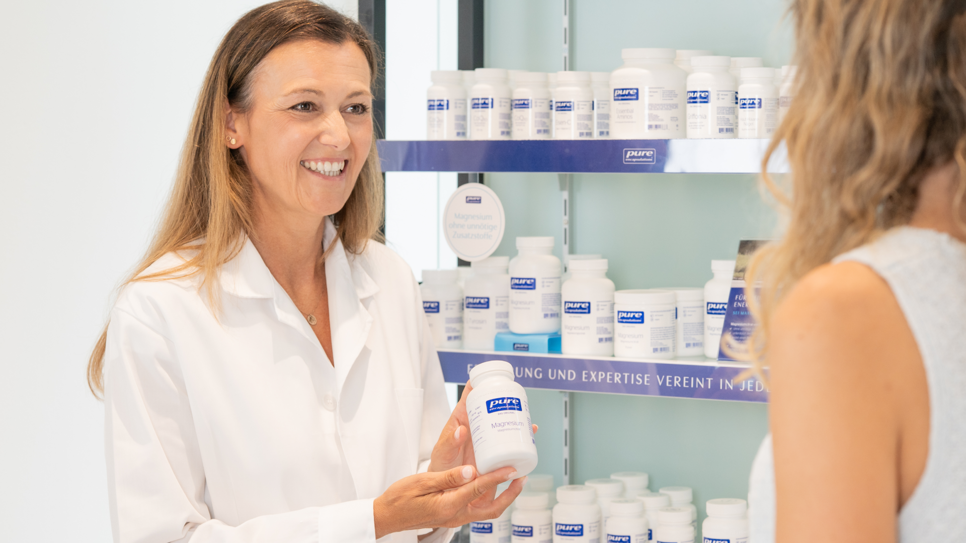 Apothekerin mit Kundin vor Regal mit Pure Bottles